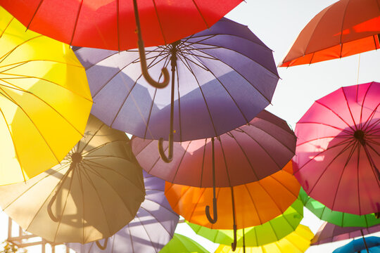 A colorful cluster of umbrellas is viewed from below against the open sky, vibrant outdoor decoration, creative festival background.