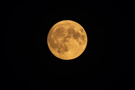 Close up of a detailed golden full moon isolated on black night sky background