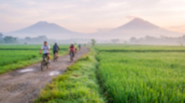 Intentional blurred view of people cycling through Indonesian rice fields and mountain scenery for travel posters, fitness brochures, and website backgrounds.
