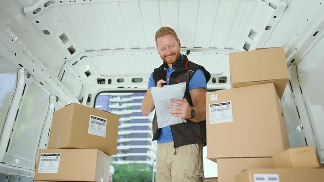 Courier holding a parcel among boxes inside a delivery van