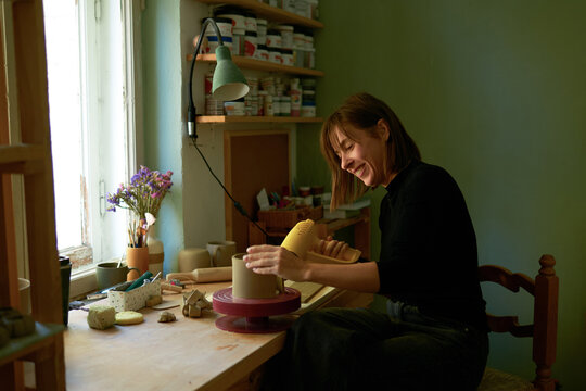  A woman shapes clay at her pottery studio workbench