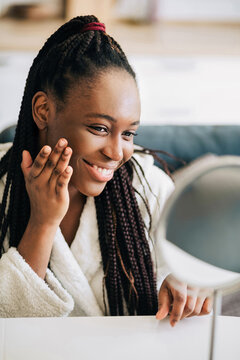 Portrait of happy african american woman looking at the mirror at home