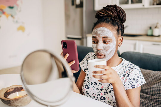 Portrait of african american woman with a face mask scrolling a phone