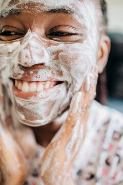 Close up portrait of african american woman washing face with foam