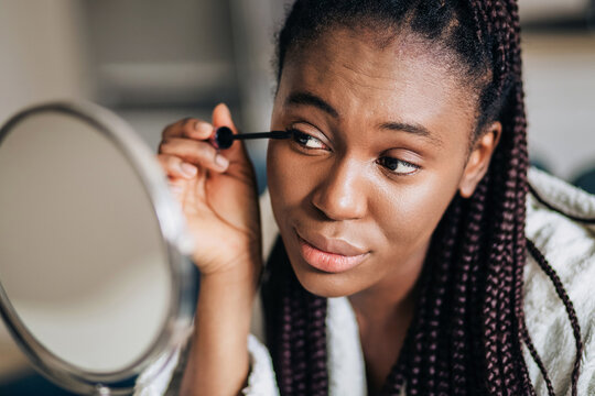 Closeup portrait of happy african american woman putting on mascara 