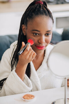 Home portrait of happy african american woman applying makeup 