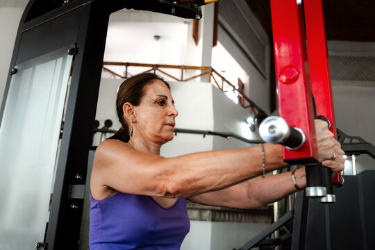 Mature Woman Training on Weight Machine at Gym