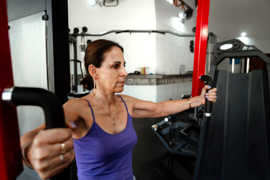 Mature Woman Training on Weight Machine at Gym