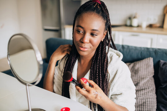 Portrait of happy african american woman applying make up 