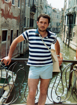 Man posing on bridge overlooking venice canal