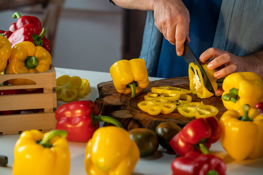 Crop chef cutting paprika at table in kitchen