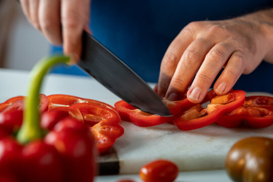 Crop chef cutting red peppers on chopping board