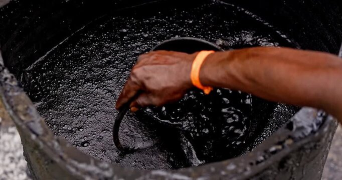 Workers Heating Hot Bitumen in a Metal Drum for Rural Road Construction and Maintenance, vertical and horizontal video