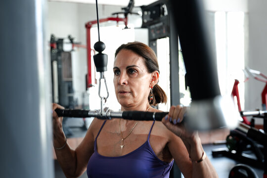 Mature Woman Training on Weight Machine at Gym