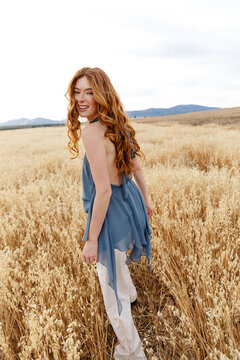 Redhead woman walking in oat field