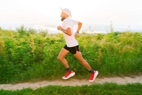 Runner Moves Quickly Along a Path in a Green Field at Sunset