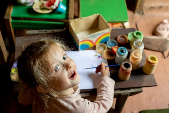 Little child painting in the children's playhouse in the garden