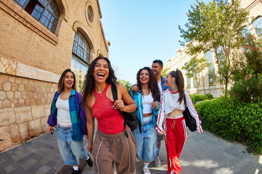 Friends enjoy a walk in the city while laughing and chatting tog