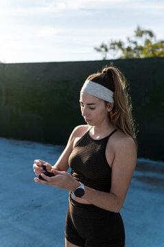 Woman holding a wireless earbud charging case outdoors