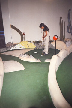 Analog film portrait of girl playing mini golf