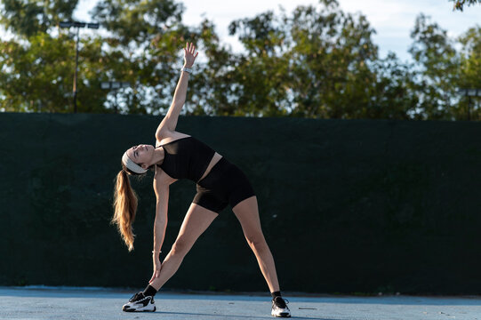 Athletic woman stretching on an urban court