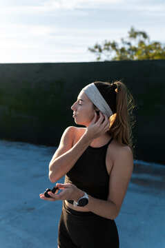 Runner placing a wireless earphone in her ear before training