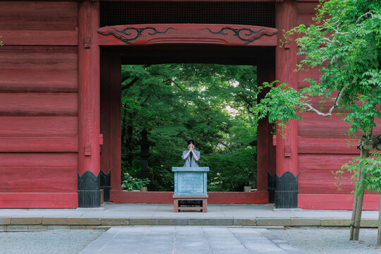 Professional Woman Praying in Front of a Japanese Temple Gate.