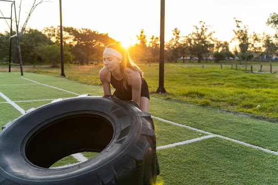 Determined woman pushing a heavy training tire