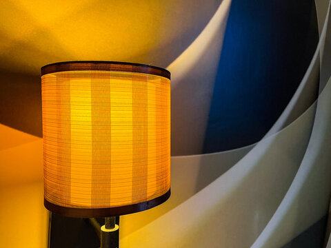 Bedside lamp glowing warmly against an artistic modern wall, creating an elegant bedroom atmosphere with contemporary decor, ambient lighting, and stylish interior design.