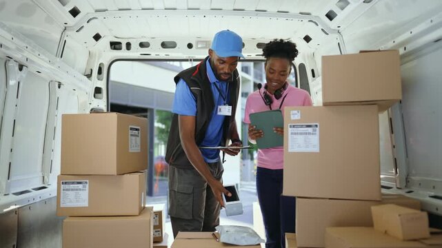 Two couriers sorting packages inside a delivery van