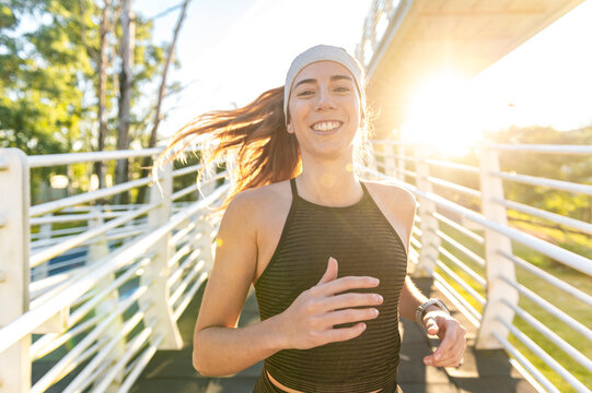 Joyful athlete running across a footbridge in evening light