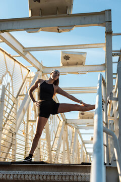 Athletic woman leg stretching on a footbridge railing
