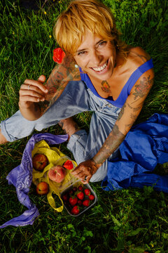 Woman enjoys fruits in a grassy area during sunny day