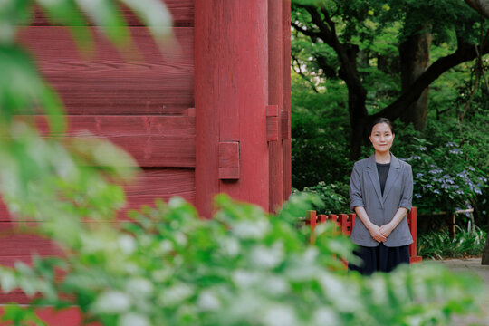 Professional Woman Standing by a Red Temple Building.