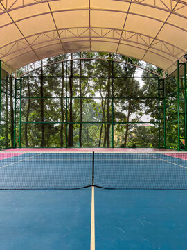 Outdoor tennis court with a grand arched roof structure, vibrant playing surface, and spacious design, showcasing modern sports facilities suitable for recreational and professional activities.