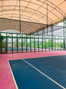 Outdoor tennis court with a grand arched roof structure, vibrant playing surface, and spacious design, showcasing modern sports facilities suitable for recreational and professional activities.