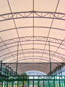 Covered sports court roof with a lightweight steel frame and translucent panels, allowing outdoor activities to continue during rainy weather while providing natural daylight and shelter.