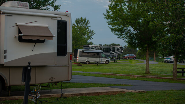 Early morning light at campsite with Rv parked under tall trees with path to sites