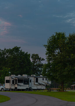 Early morning light at campsite with Rv parked under tall trees with path to sites