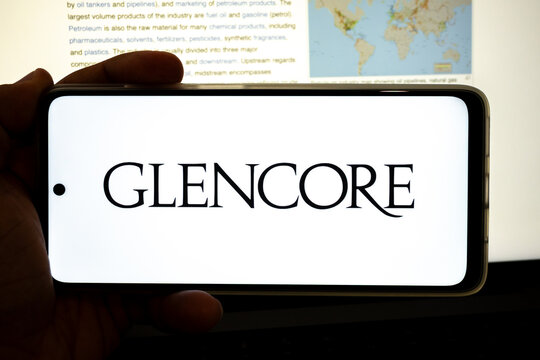 Hand holding device displaying glencore company logo