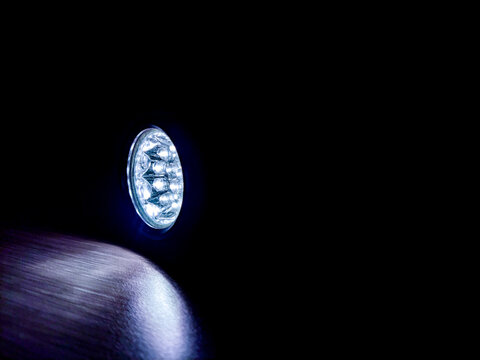 Flashlight beam shining in a dark room, creating a focused light spot and strong contrast, highlighting visibility, direction, and minimal illumination in a low-light environment.