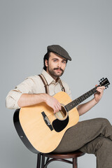Obraz premium Charming gentleman with a moustache playing guitar in a stylish retro outfit
