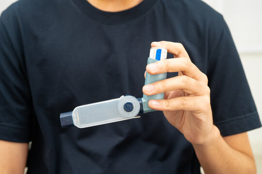 Asthma and chronic obstructive pulmonary disease COPD, Asian young man using metered dose inhaler MDI.