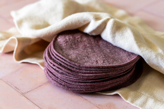 Blue corn tortilla shells wrapped in a cloth napkin on a tile surface