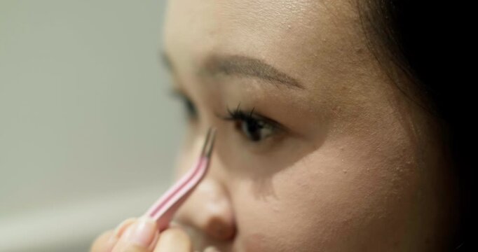 Close-up of young Asian woman putting on false eyelashes