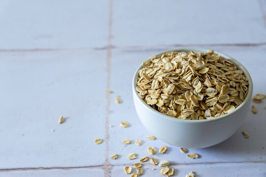 Old fashion oats in a white ceramic bowl on a tile surface 