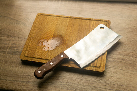 Kitchen knife and chopping board on wooden table. Toned.