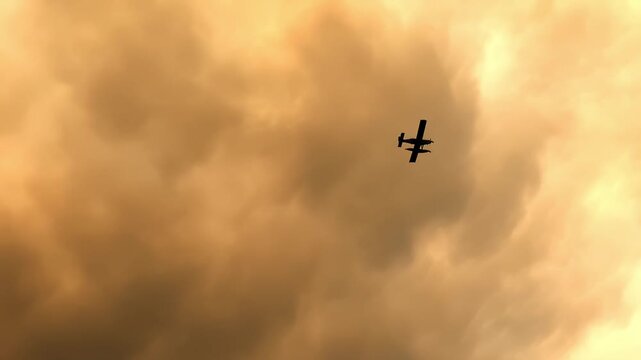 The silhouette of a forest firefighting tanker aircraft moves against a sky filled with toxic smoke.