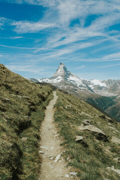 Winding path on a grassy hillside with the iconic matterhorn mountain in the distance