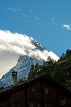 Matterhorn mountain peak with snow and clouds above a traditional wooden chalet in zermatt